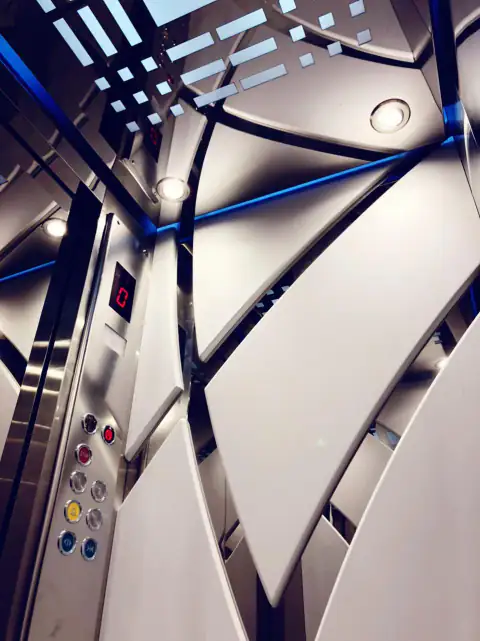 Curved mirror-steel cabin wall with blue LED accents and button panel
