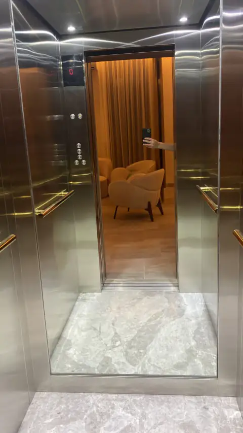 Cabin with stainless and mirror walls, marble-look floor, view through to a lounge