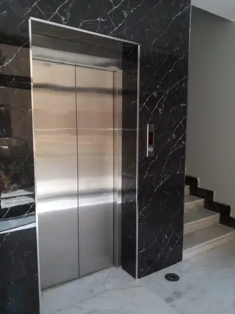 Stainless steel double doors in a black marble surround at a stairwell