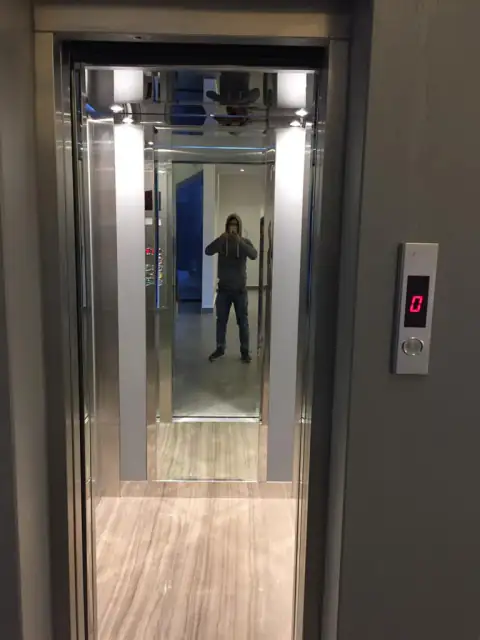 Stainless steel landing door with call button in an entrance hall