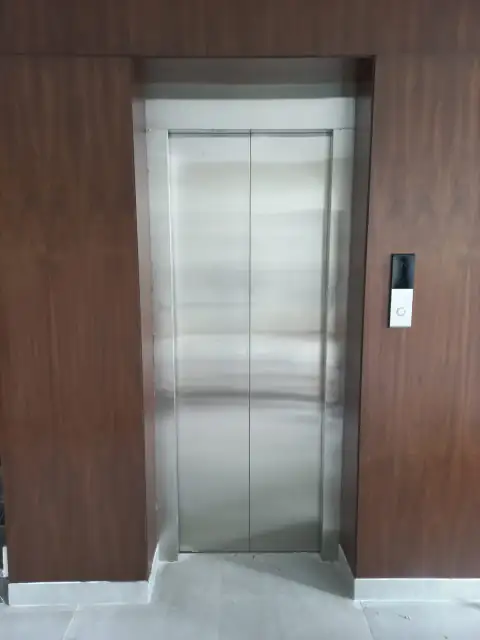 Stainless steel landing door set in a wood panel wall