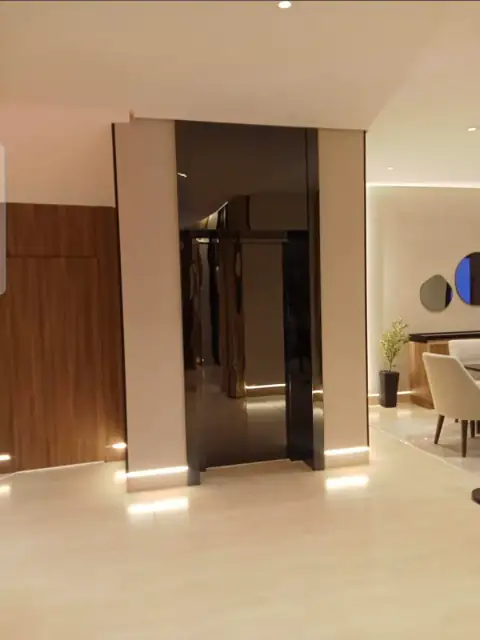 Lift enclosure in a modern hall with tinted glass door and floor LED lights