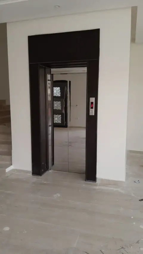 Dark wood-framed landing opening with stainless door, building under construction