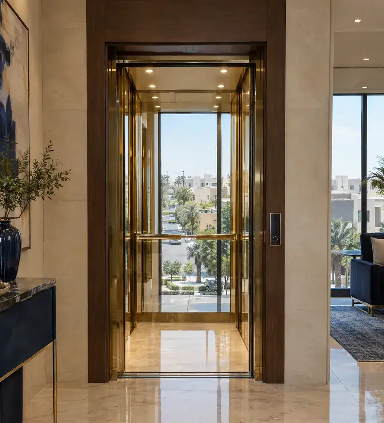 Home lift with a gold mirror cabin, doors open onto a marble hall